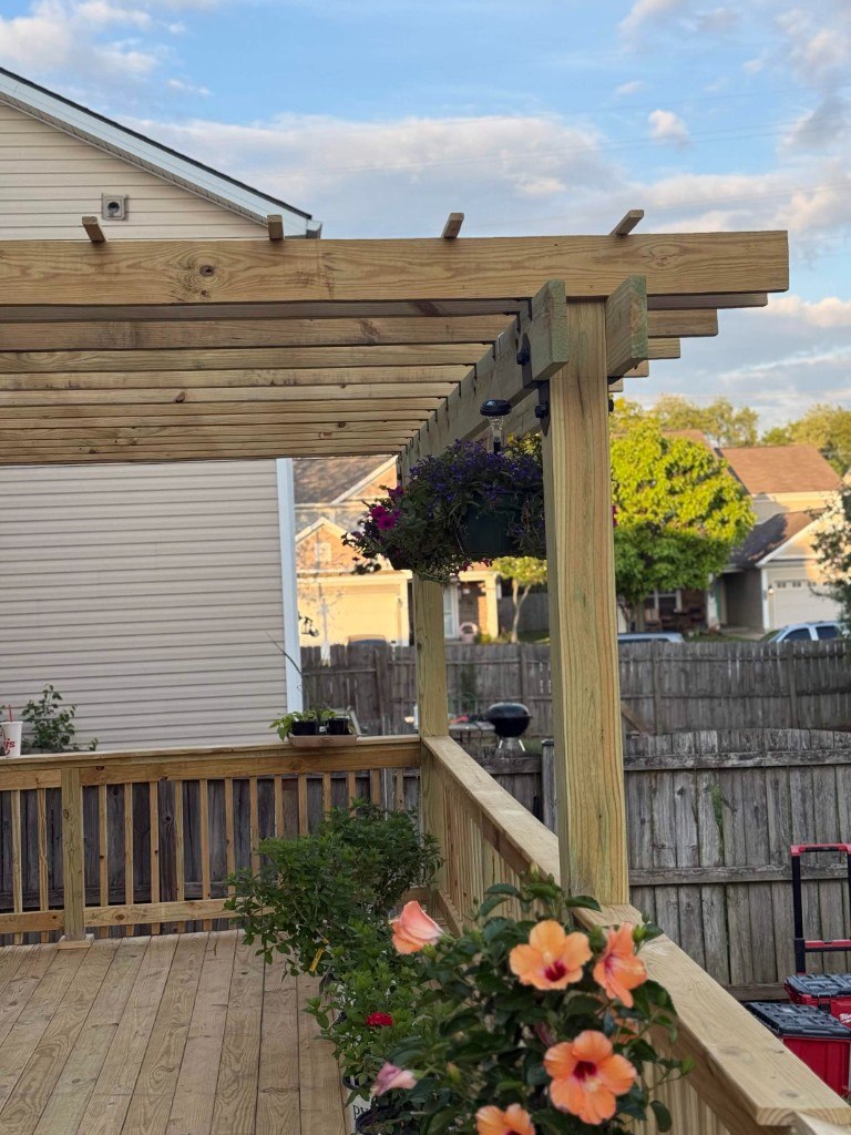 Custom pressure-treated pergola with hanging flower baskets over wood deck in Lexington KY by Big Blue Fence & Deck